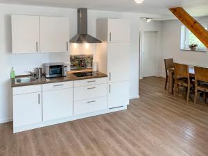 a kitchen with white cabinets and a dining room at Apartment Borkum by Interhome in Westerholt