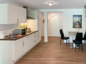 una cucina con armadi bianchi e sedie nere in una stanza di Apartment Langeoog by Interhome a Westerholt