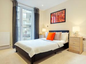 a bedroom with a bed with orange pillows and a window at Apartment Canary Gateway- Canary Wharf by Interhome in London