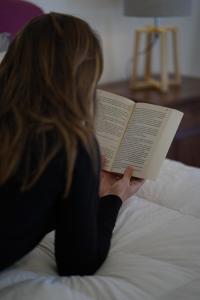 Kobieta leżąca na łóżku czytająca książkę w obiekcie B&B Bivona w mieście Mazara del Vallo