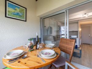 a wooden table with plates and wine glasses on it at Apartment Les Océanes by Interhome in Damgan