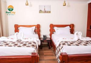 1 Schlafzimmer mit 2 Betten mit weißer Bettwäsche und einem Tisch in der Unterkunft Pori City Hotel in Nairobi