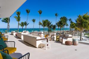 a patio at the beach with chairs and palm trees at Tropical Deluxe Princess - All Inclusive in Punta Cana