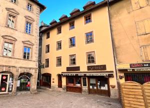 un grande edificio giallo con negozi sul lato di T3 au cœur du centre historique de Briançon #2 a Briançon