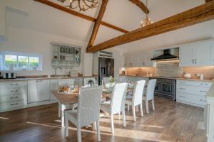 uma cozinha com uma mesa de madeira e cadeiras brancas em Yew Tree Cottage em Longborough
