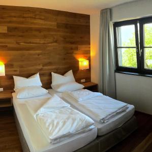1 Schlafzimmer mit 2 Betten mit weißer Bettwäsche und Kissen in der Unterkunft Hotel Café Schatz in Hohenems