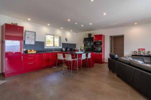 una cocina con armarios rojos y un bar con taburetes en Villa vue mer 4 chambres, en Olmeto