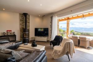 Una sala de estar con un sofá y sillas y un televisor. en Villa vue mer 4 chambres, en Olmeto