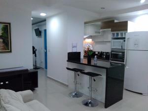 a kitchen with a black counter and a white refrigerator at Apartamento completo A42 Flat Centro in Mogi das Cruzes