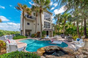 an exterior view of a house with a swimming pool and palm trees at Chateau de la Mer in Jensen Beach