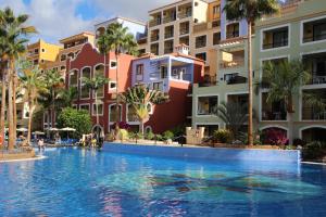 a swimming pool in a resort with palm trees and buildings at Bahia Principe Sunlight Tenerife - All Inclusive in Adeje