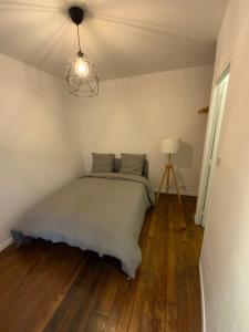 a bedroom with a bed and a lamp on a wooden floor at Quartier bas Montreuil à 3minutes du métro in Montreuil
