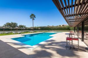 a pool with a table and chairs and a palm tree at Interpass Vau Hotel Apartamentos in Portimão