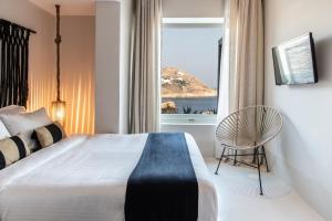 a bedroom with a bed and a chair and a window at Nimbus My Aktis in Super Paradise Beach