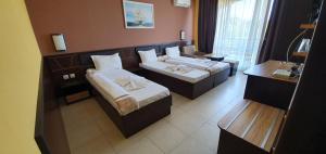 a hotel room with two beds and a desk at Hotel Luxor in Lozenets