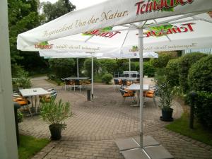 un patio con mesas y sombrillas con mesas y sillas en Sportpark Jürgen Fassbender, en Eggenstein-Leopoldshafen