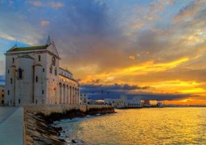 een gebouw naast een waterlichaam met een zonsondergang bij Casa Vacanza -Trani centro in Trani