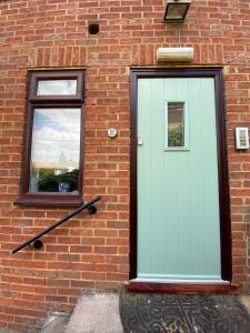 a green door on the side of a brick building at Pound Corner in Godalming