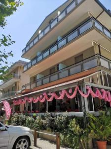 een restaurant met roze luifels voor een gebouw bij Hotel Brezza in Rimini