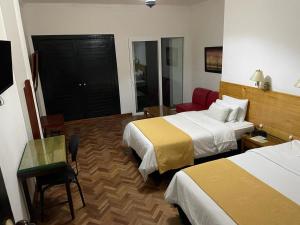 Habitación de hotel con 2 camas, mesa y silla en Hotel Camino Real Popayán Colombia, en Popayán