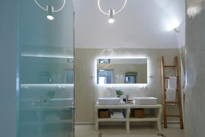 ein Bad mit einer Dusche, 2 Waschbecken und einem Spiegel in der Unterkunft U & ME SUITES in Fira