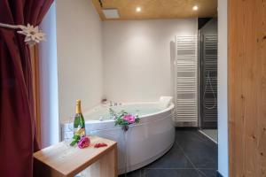 a bathroom with a tub and a bottle of champagne at Baita Velon in Vermiglio