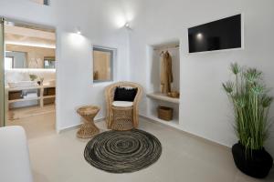 a bathroom with two chairs and a tv on a wall at U & ME SUITES in Fira