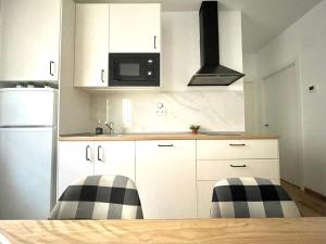 a kitchen with white cabinets and black and white appliances at Trauko Flat Optional parking 12day EBI in Bilbao