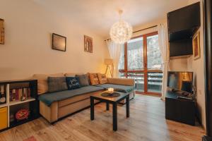 a living room with a couch and a table and a tv at Max Holiday Apartment in Pamporovo