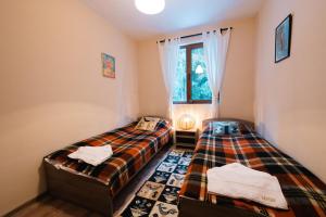 two twin beds in a room with a window at Max Holiday Apartment in Pamporovo