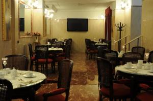 a dining room with tables and chairs and a television at Hotel Villa Maria in Naples