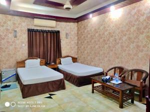 a hotel room with two beds and a table at Hotel Royal Avenue in Chittagong