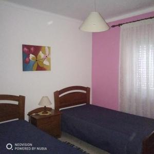 Apartamento Central في فيلا ريال دي سانتو انطونيو: سريرين في غرفة بجدران وردية وأرجوانية