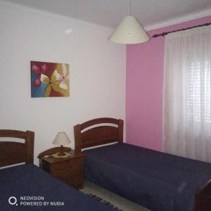 two beds in a room with pink and purple walls at Apartamento Central in Vila Real de Santo António +6 photos