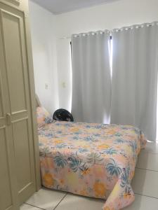 1 dormitorio con 1 cama con colcha de flores en Casa de aluguel Gregório, en Imbituba