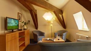 ein Wohnzimmer mit einem TV, 2 Stühlen und einem Tisch in der Unterkunft Hotel Lekker in Neumagen-Dhron