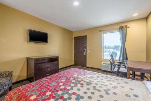 Dormitorio con cama, escritorio y TV en Southern Inn and Suites, en Spartanburg