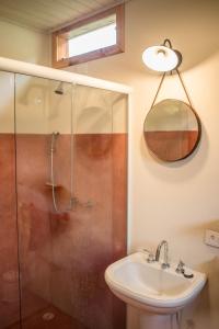 a bathroom with a shower and a sink and a mirror at Cabana Arbosana in São Bento do Sapucaí