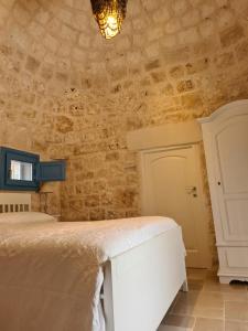 a bedroom with a white bed and a stone wall at I trulli di Uma in Carovigno