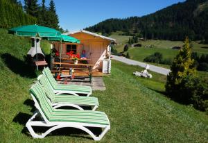 un groupe de chaises longues assises dans l'herbe devant une cabine dans l'établissement Landhaus Sonnenzauber, à Oberau