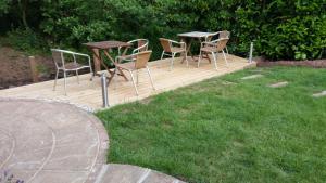 a wooden deck with chairs and tables in a yard at Riverwood Retreat - Self Contained Lux Apartment, Close to the Celtic Resort in Kemeys Inferior