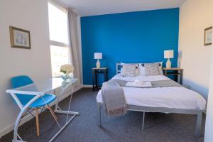 Dormitorio azul con cama y mesa de cristal en Spacious 5 Bed House, perfect for groups, great location, en Liverpool