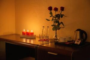 uma mesa com duas velas e um vaso com rosas em Neptun em Legnica