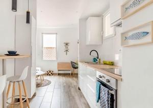 a kitchen with white cabinets and a table and chairs at Studio contemporain + Terrasse - Port de l'Estaque in Marseille