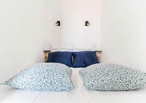 ein Bett mit zwei Kissen und einer weißen Wand in der Unterkunft Studio contemporain + Terrasse - Port de l'Estaque in Marseille