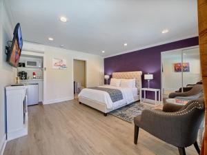 a bedroom with a bed and two chairs and a tv at Little Paradise Hotel in Palm Springs