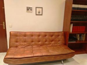 un sofá de cuero marrón sentado junto a un estante de libros en DZ Apartamento en Alicante