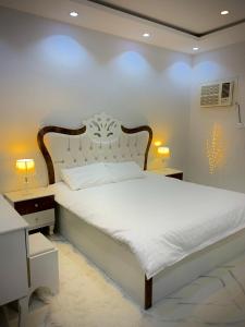 1 dormitorio con 1 cama blanca y 2 mesitas de noche en منتجع مرايا, en Al Ula
