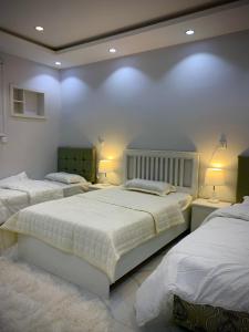 1 dormitorio con 2 camas, sábanas blancas y luces en منتجع مرايا, en Al Ula