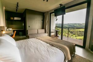 a bedroom with a large bed and a balcony at Pousada Casa Bambu in Cunha